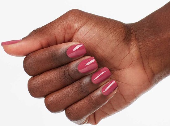 Een donkere huid met nagels gelakt in een perzikroze kleur.