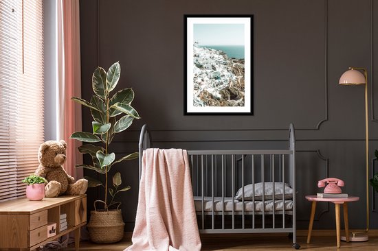 Maison blanche avec mer bleue en arrière-plan, dans un cadre noir.
