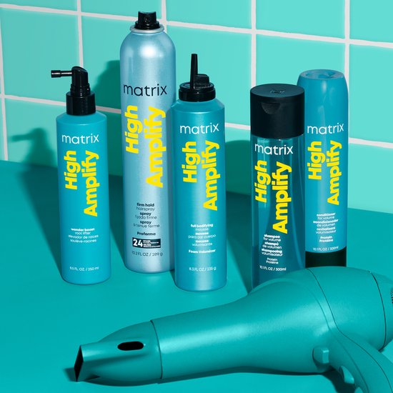 Un ensemble de produits capillaires Matrix High Amplify, y compris un sèche-cheveux. Sur un fond turquoise.