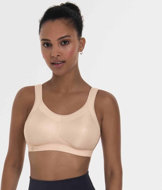 Lichtroze sportbeha met voorgevormde cups en verstelbare bandjes. Een vrouw draagt de beha met een donkere sportbroek.