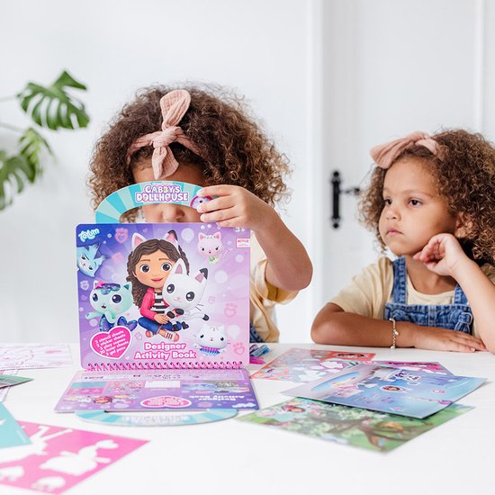 Deux filles avec des bandeaux regardent un livre d'activités créateur Gabby's Dollhouse.