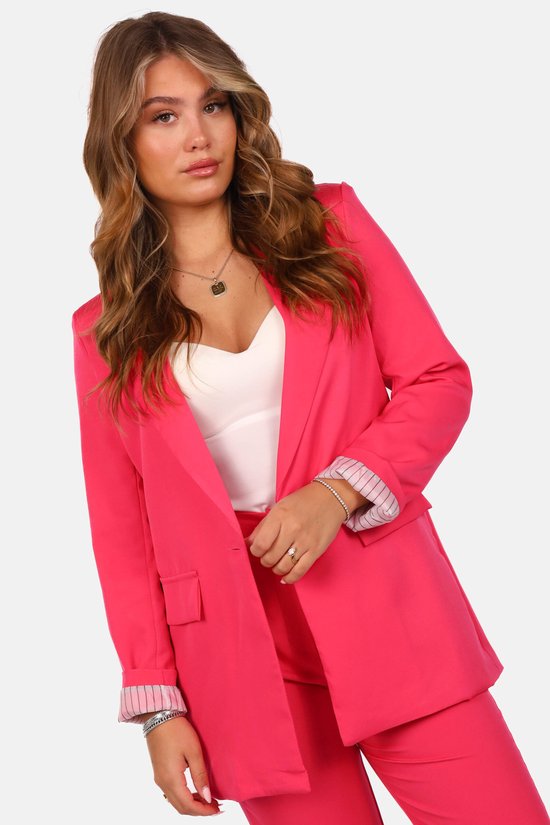 Close-up van model in felroze getailleerde blazer met gestreepte mouwvoering over een witte top.