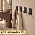 Zwarte handdoekhaken aan een muur met twee geweven handdoeken, beige en crème van kleur.