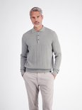 Model draagt een grijze polo met verticale strepen en textuur, gecombineerd met een beige broek.