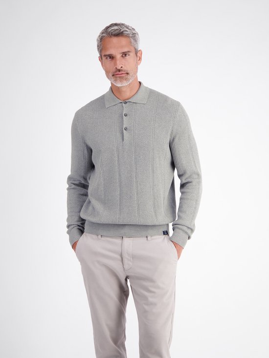 Model draagt een grijze polo met verticale strepen en textuur, gecombineerd met een beige broek.