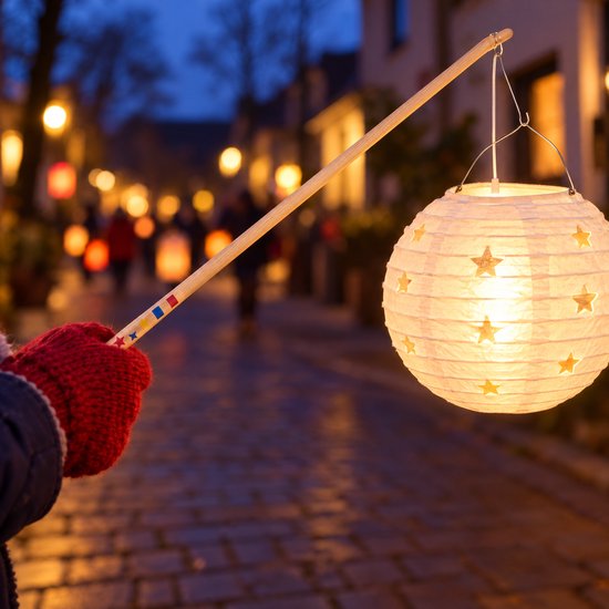 Hand in een rode want houdt een houten stok vast met een brandende lampion met sterpatroon in een verlichte straat.