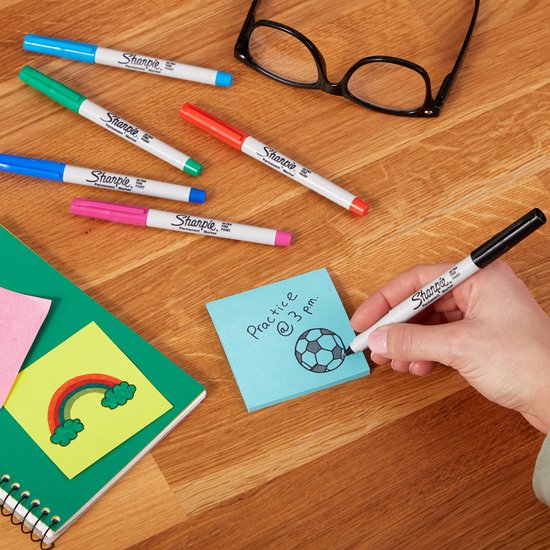 Hand tekent een voetbal op blauw post-it met diverse Sharpie markers.