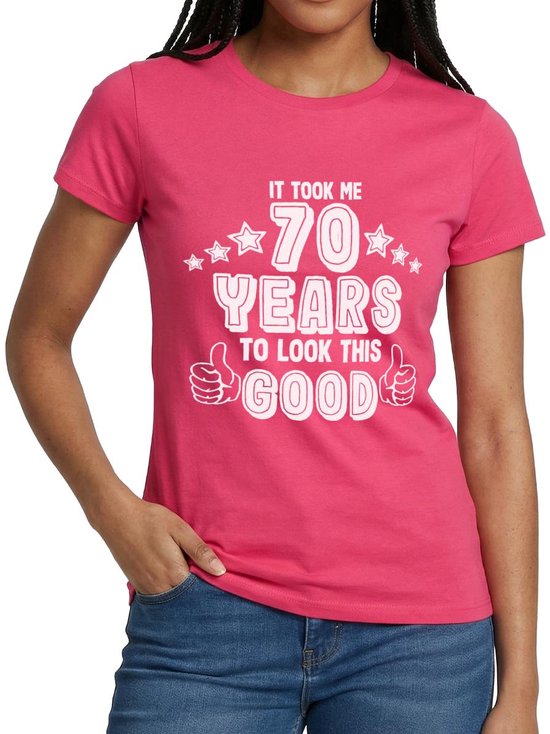 Mannequin portant un T-shirt rose avec l'inscription blanche 'IT TOOK ME 70 YEARS TO LOOK THIS GOOD' et un jean.
