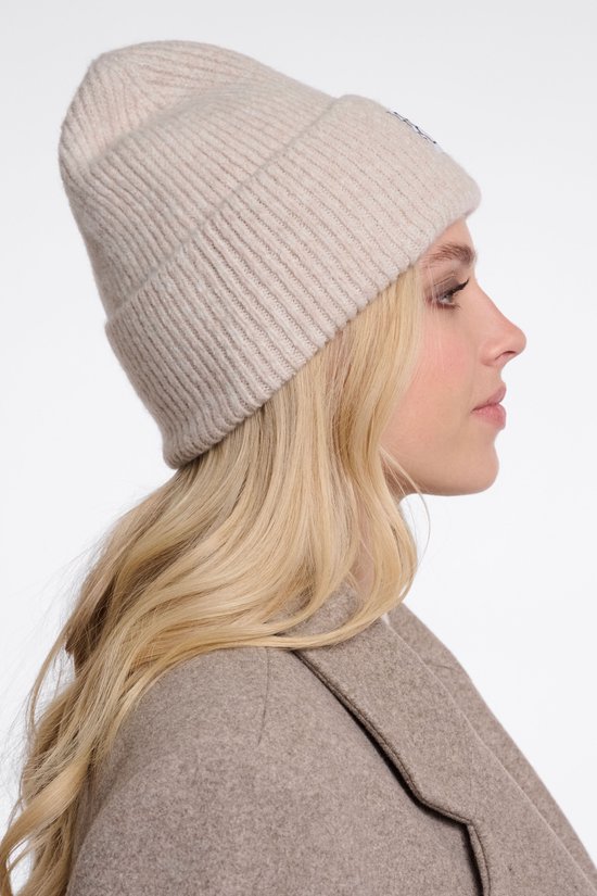 Zijaanzicht van model met blond haar in een beige gebreide muts met 'RP' logo.