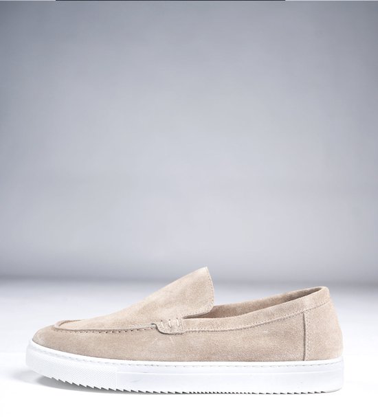 Zijaanzicht van een beige suède loafer met een witte rubberen zool.