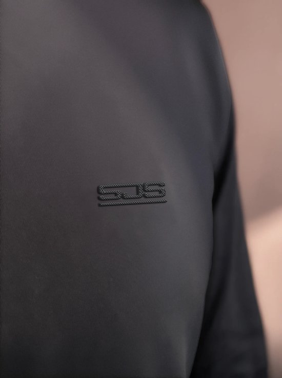Detail van het logo 'SJS' op een zwart sportshirt.