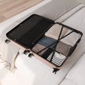 Een open rosegouden koffer op een bed, gevuld met kleding.