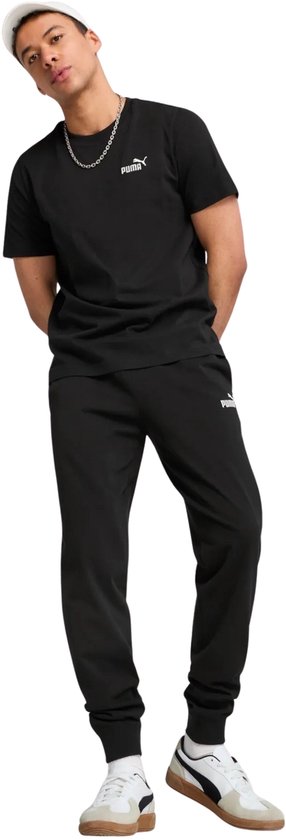 Man draagt een zwarte PUMA t-shirt en zwarte trainingsbroek, met een witte pet.