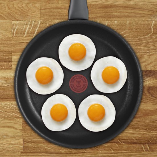 Zwarte Tefal koekenpan met vijf gebakken eieren in een cirkel, met rode Thermo-Signal in het midden.