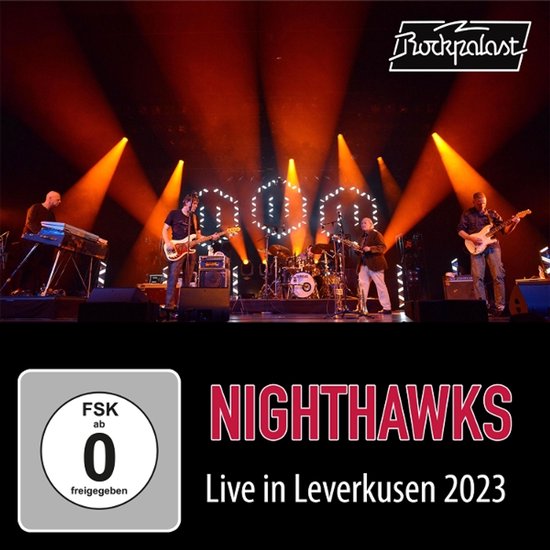 Band op podium met felle oranje lichten en "NIGHTHAWKS Live in Leverkusen 2023" tekst.
