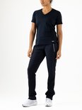 Model in een donkerblauwe V-hals sportshirt en bijpassende trainingsbroek met witte sneakers.
