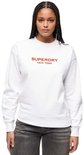 Femme portant un sweat Superdry blanc avec l'inscription rouge "SUPERDRY NEW YORK".