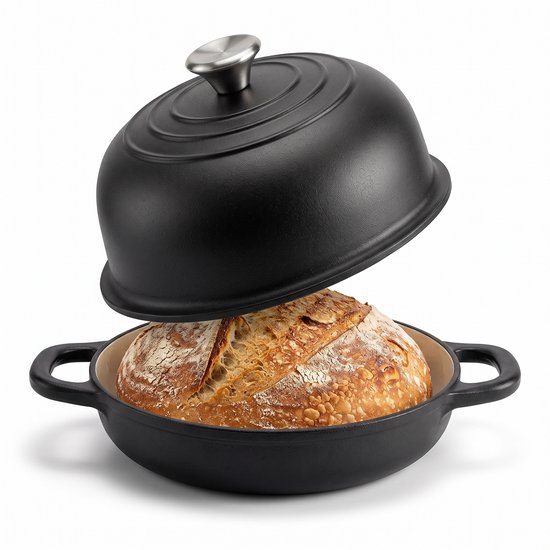 Zwarte gietijzeren pan met openstaand koepeldeksel waarin een versgebakken zuurdesembrood zit.