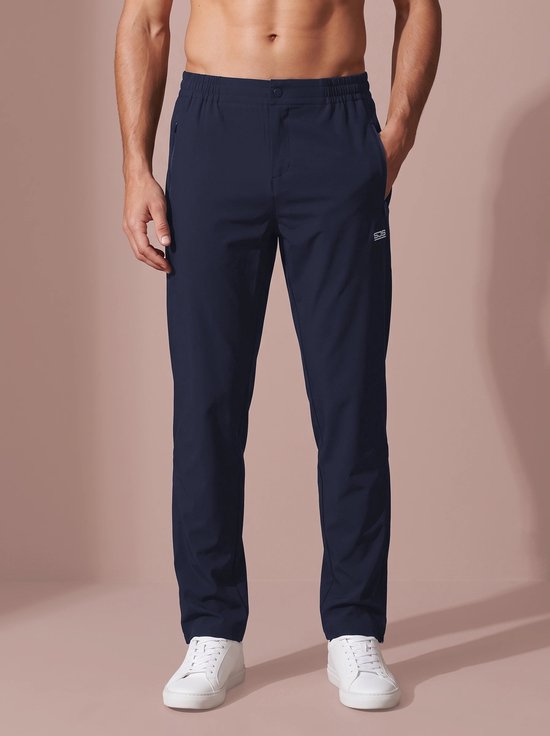 Vooraanzicht van het model in een marineblauwe sportbroek met elastische taille en "SJS"-logo op de heup.