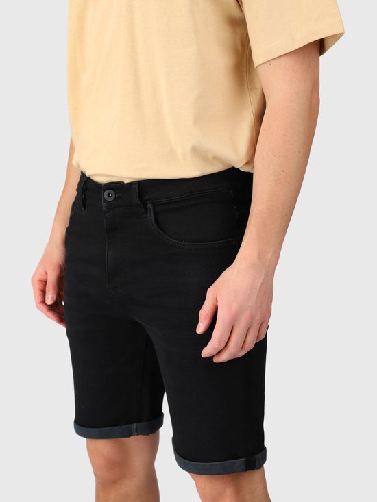 Zijaanzicht van zwarte denim shorts met opgerolde zomen, getoond op een model met een beige T-shirt.