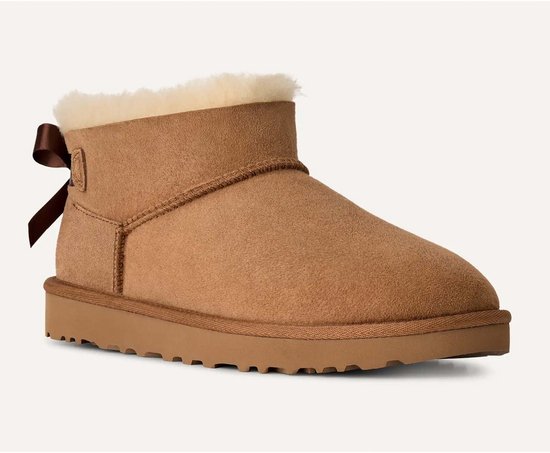 Cognackleurige UGG Ultra Mini laars van suède met een crèmekleurige voering en een strikdetail op de hiel.