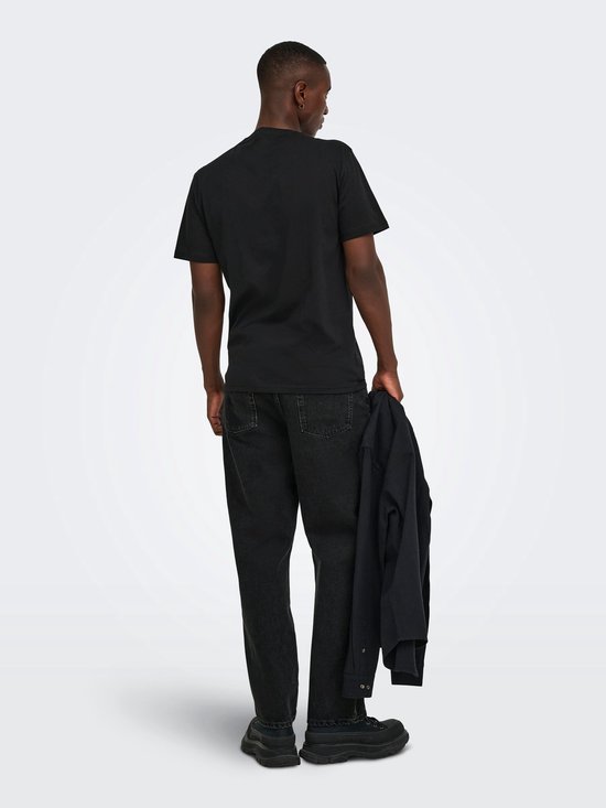 Achterkant van een model in zwarte jeans met rechte pijpen en een zwart T-shirt, vasthoudend aan een zwarte jas.