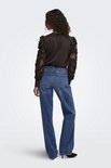 Model van achteren in bruine trui met bloemige, doorschijnende mouwen en jeans.