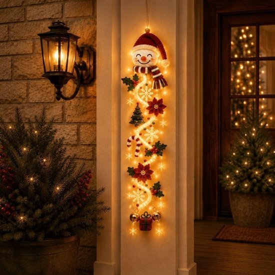 Verlichte kerstdeurhanger met sneeuwpop, poinsettia's, suikerstokjes, dennenboompjes en gouden klokjes aan de muur.