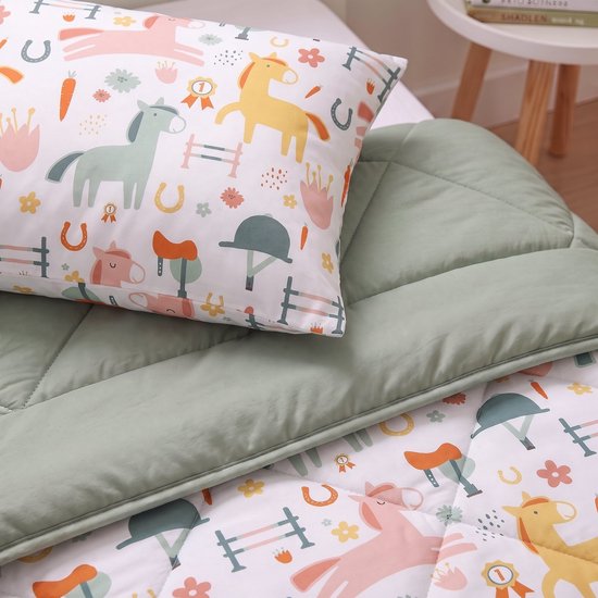 Close-up van het dekbed met paardenmotief, inclusief een zachtgroene rand en een kussensloop met hetzelfde patroon.