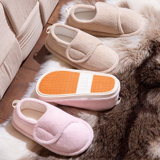 Collectie beige en roze pluche pantoffels met antislipzolen op een harige ondergrond.