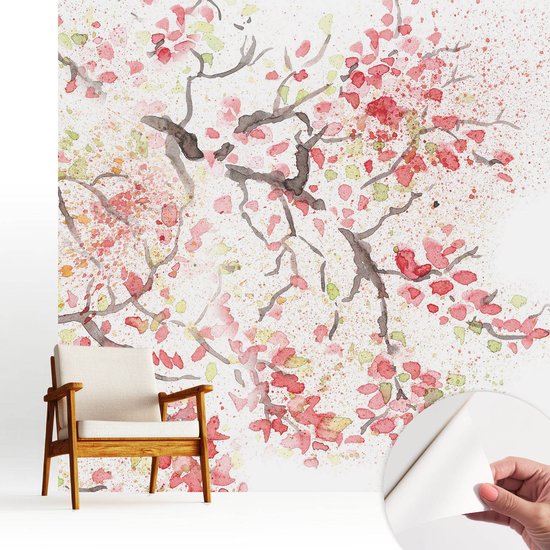 Zelfklevend behang met roze aquarel bloesemtakken, retro stoel en een hand die het behang losmaakt.