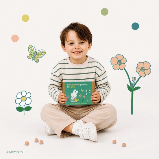 Een lachende jongen in gestreepte trui en corduroy broek, zittend met een doosje 'a butterfly garden for you'.