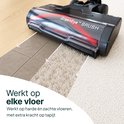 Zwarte stofzuigerkop met rode borstel beweegt over tegels en dan een beige tapijt.