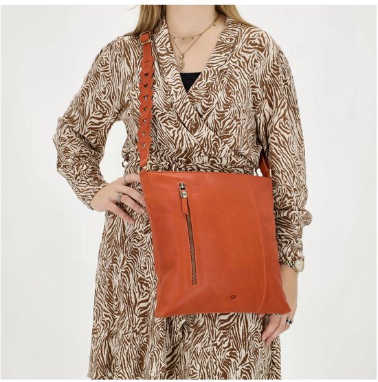 Model draagt een oranje leren schoudertas met een gevlochten band, met een ritssluiting aan de voorzijde.