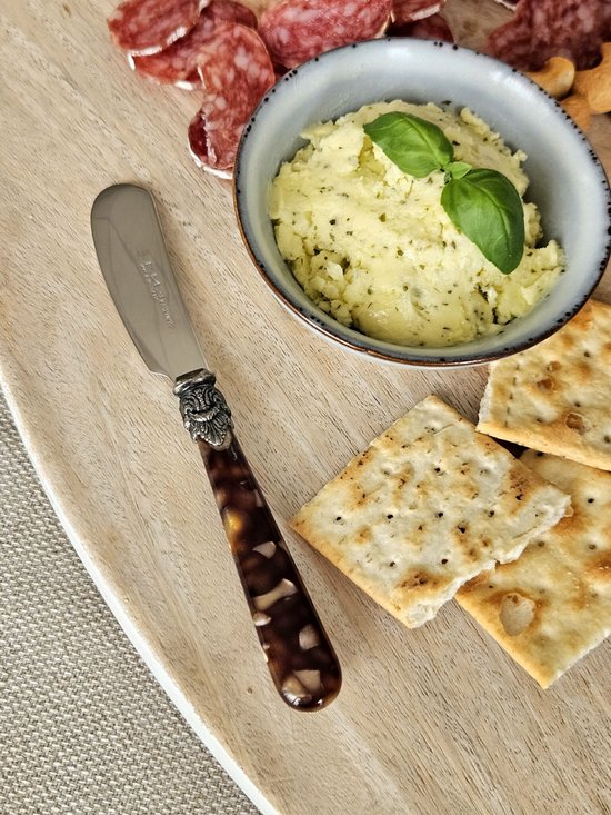 Houten plank met boterhapjes, crackers, salami en een botermes met bruin schildpadprint handvat.