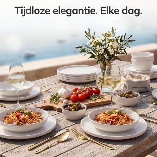 Buiten gedekte tafel met 2 witte borden met spaghetti, witte wijnglazen, olijven en bloemen.