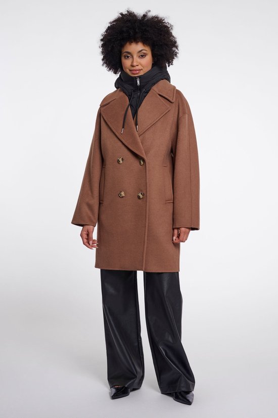 Model draagt een bruine jas met dubbele knopen over een zwarte hoodie.