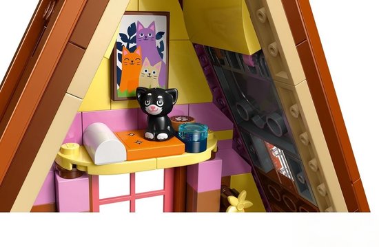 Close-up van een LEGO Friends hut met twee katten-schilderijen, een zwarte kat en accessoires.