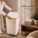 Een vrouw tilt de beige wasmand met deksel op. De wasmand is licht in gewicht, makkelijk te tillen en verplaatsen.