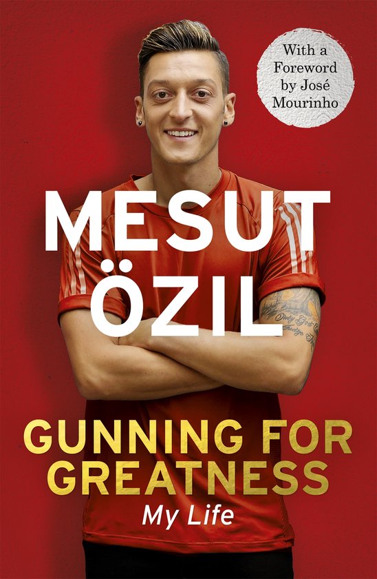 Mesut Özil met gekruiste armen op de voorkant van zijn boek 'Gunning for Greatness: My Life'. Hij draagt een rode sportshirt met witte strepen.