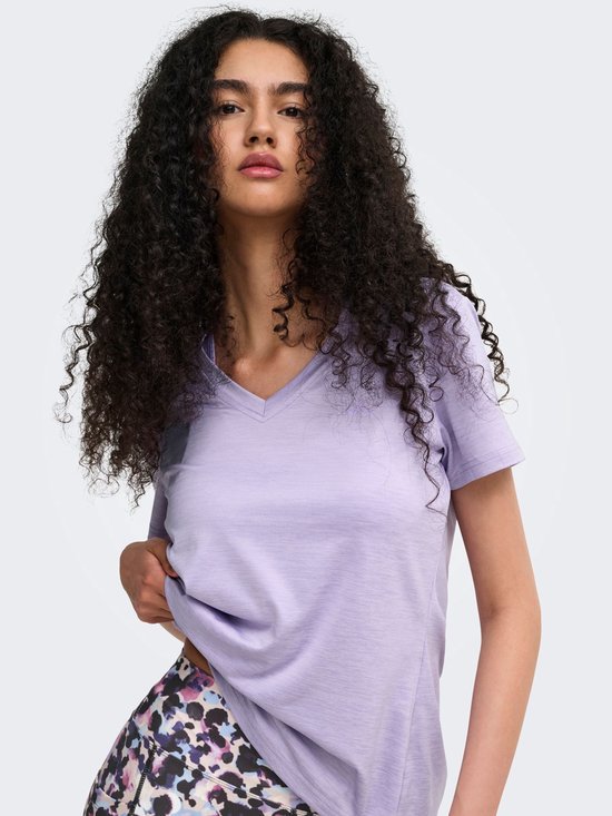 Model draagt een lichtpaars V-hals T-shirt en een legging met veelkleurig abstract patroon. Close-up van voren.