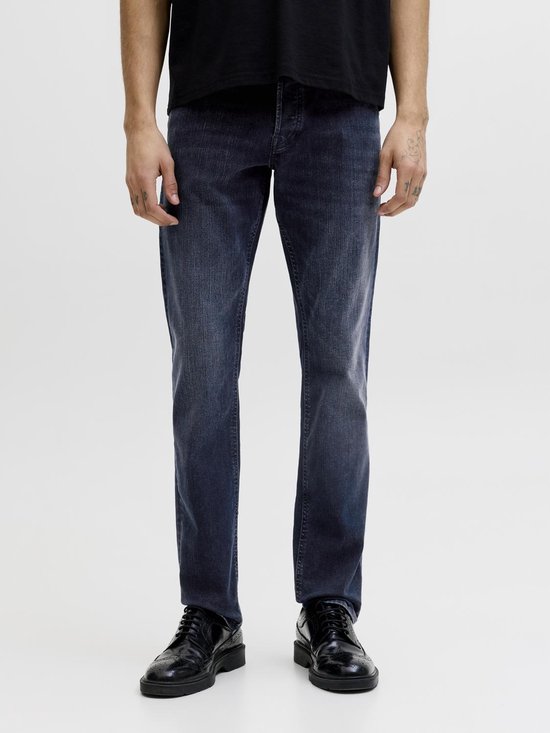 Man met donkerblauwe spijkerbroek en zwarte schoenen.