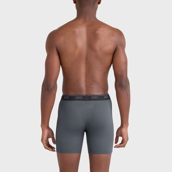 Model van achteren gezien in grijze SAXX boxershort met subtiel ruitpatroon en SAXX-logo op de zwarte tailleband.