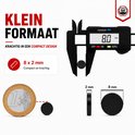 Een digitale schuifmaat meet een kleine, zwarte, platte magneet van 8x2mm, naast een euro munt.
