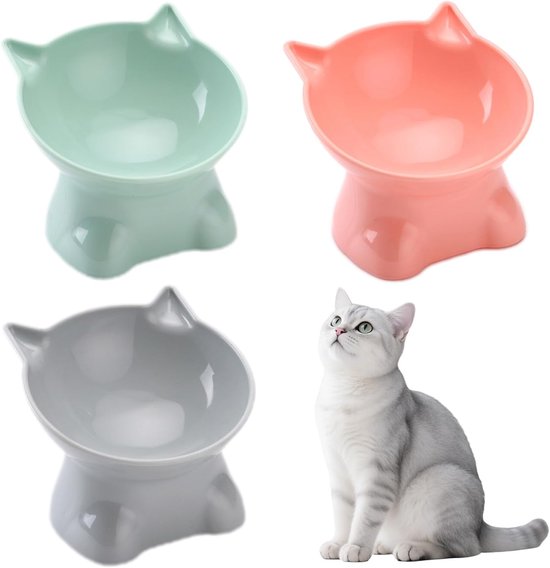 Drie schuine kattenbakken in groen, roze en grijs. Een zittende witte kat kijkt omhoog.