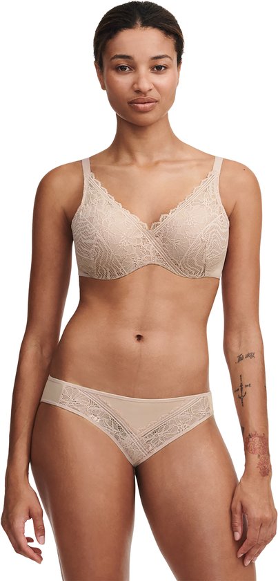 Model draagt een beige kanten bh en slip. De bh heeft een V-hals met kanten rand.