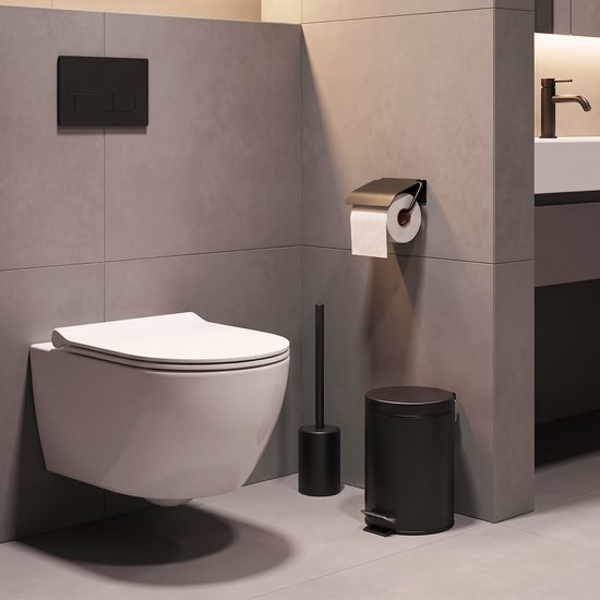 Strakke badkamer met witte hangtoilet, zwarte toiletborstel in houder, zwarte prullenbak en bronzen kraan.