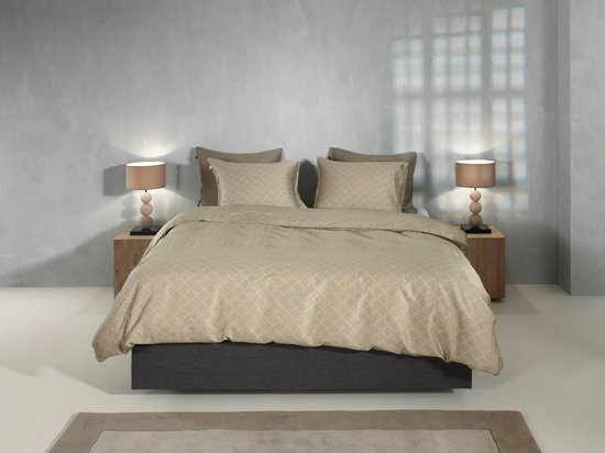 Een tweepersoonsbed opgemaakt met beige beddengoed met ruitpatroon, twee kussenslopen en nachtkastjes.