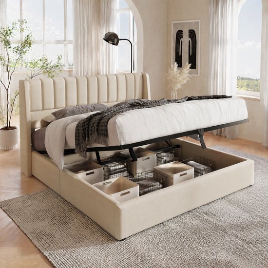 Lit tapissé beige avec sommier relevable, paniers avec rangement en dessous, dans une pièce lumineuse.