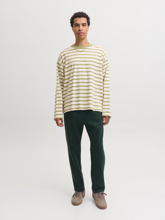 Man in gestreept groen-wit T-shirt met lange mouwen en donkergroene joggingbroek.